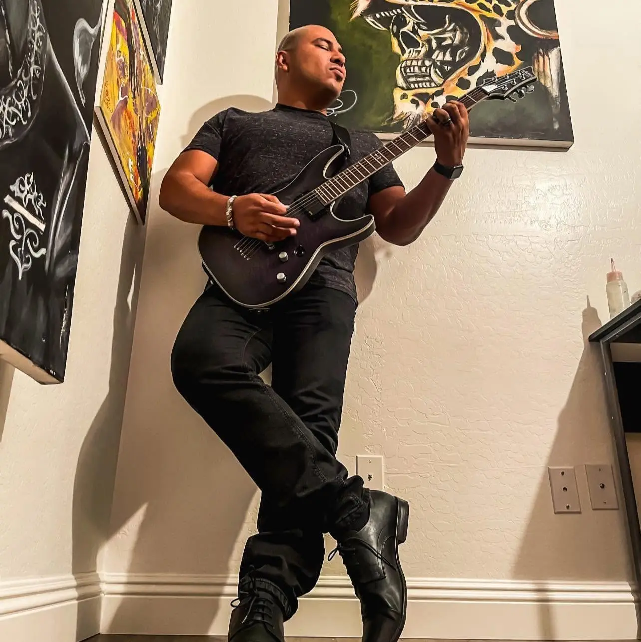 Voz Luis Sanchez playing guitar surrounded by his paintings